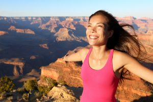 Happy freedom woman tourist in Grand Canyon smiling free in happiness during summer travel trip in Grand Canyon, South Rim, Arizona, USA.